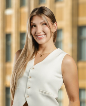 Woman smiling in professional attire outdoors.